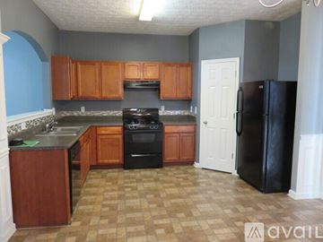 Lawrenceville house for rent - A kitchen with a black refrigerator and wooden cabinets.