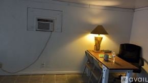 Riverside apartment for rent - A lamp on a desk in a room with a white wall and a window vent.