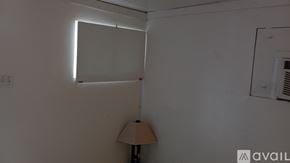 Riverside apartment for rent - A lamp sits on a table in a room with a white wall and a window.