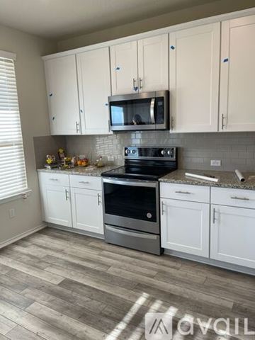 Leander house for rent - A kitchen with white cabinets and a black stove top oven.