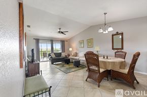 Punta Gorda condo for rent - A kitchen with white cabinets and appliances, a table with a blue plate on it, and a window with blinds.