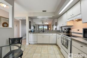 Punta Gorda condo for rent - A pool with two chairs and a table is surrounded by a grassy area.