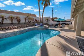 Lake Havasu City house for rent - A pool surrounded by palm trees and a stone wall.