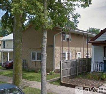 La Crosse apartment for rent - A house with a brown siding and white trim is surrounded by a wooden fence.