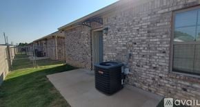 Hewitt apartment for rent - A black air conditioning unit sits on a concrete slab outside a brick building.