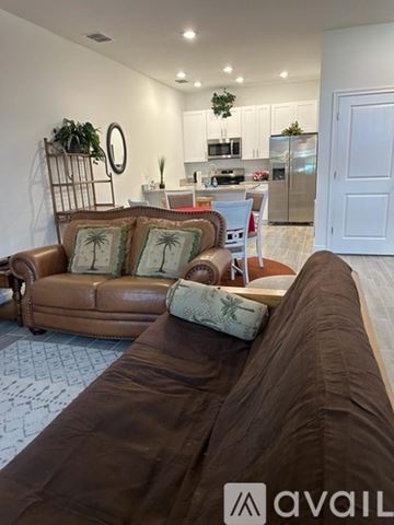 Poinciana house for rent - A living room with a brown couch and a kitchen in the background.