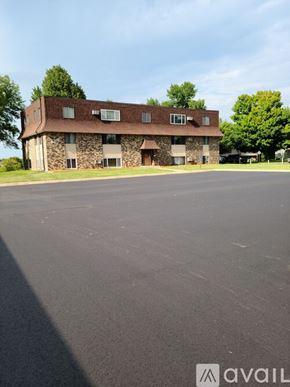New Prague apartment for rent - A stone building with a brown roof and a parking lot in front.