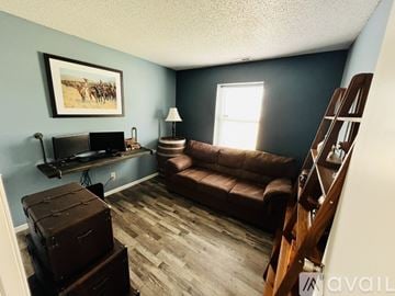 Noblesville house for rent - A living room with a brown couch, a flat screen TV, a wooden staircase, and a painting on the wall.