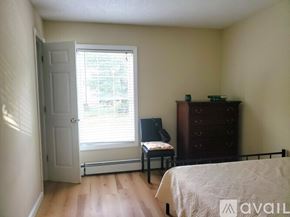 Worcester townhouse for rent - A bedroom with a bed, chair, and window.