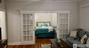 Tampa apartment for rent - A bedroom with a bed, a couch, and a window with blinds.