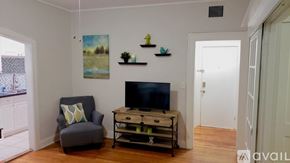 Tampa apartment for rent - A living room with a grey armchair, a television, and a painting on the wall.