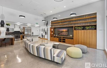 San Diego condo for rent - A living room with a long couch and a television mounted on the wall.