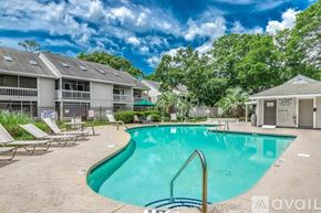 Little River condo for rent - A swimming pool surrounded by lounge chairs and trees.