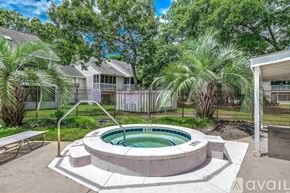 Little River condo for rent - A hot tub is surrounded by a concrete patio and a black fence.