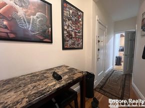 Boston apartment for rent - A hallway with a table and two pictures on the wall.