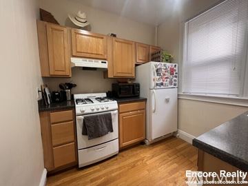 Boston apartment for rent - A kitchen with wooden cabinets and a white stove top oven.