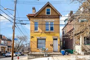 Pittsburgh house for rent - A yellow house with a red roof is in front of a blue street sign.