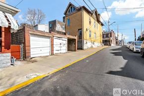 Pittsburgh house for rent - A street view with a yellow building on the right and a white car parked on the right side of the street.
