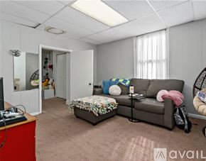 Pittsburgh house for rent - A living room with a grey couch, a red cabinet, and a small ottoman.