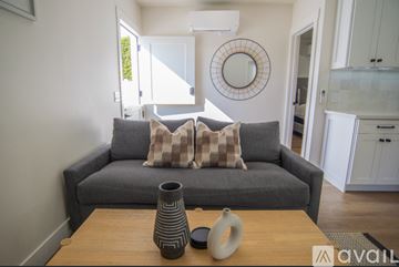 Oceanside house for rent - A grey couch with a round mirror above it in a living room.