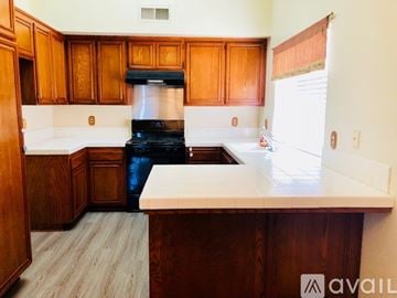Palmdale house for rent - A kitchen with wooden cabinets and a black stove top oven.