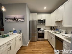 Boston apartment for rent - A kitchen with white cabinets and a wooden floor.