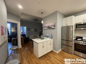 Boston apartment for rent - A kitchen with white cabinets and a wooden floor.