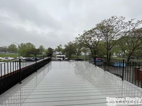 Boston apartment for rent - A wet walkway leads to a building with trees on either side.