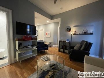Boston apartment for rent - A modern living room with a glass coffee table and a black leather chair.