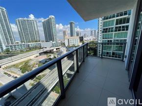 Miami condo for rent - A balcony overlooks a cityscape with tall buildings and a highway.