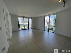Miami condo for rent - A spacious room with tiled flooring and sliding glass doors leading to a balcony.