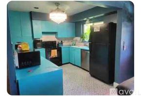 Dania Beach house for rent - A kitchen with a black refrigerator and a blue island.