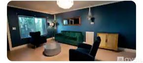 Dania Beach house for rent - A living room with a green couch and a grey ottoman.