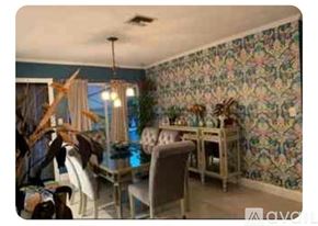 Dania Beach house for rent - A dining room with a floral wallpaper and a table set for a meal.