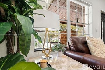 Miami house for rent - A living room with a brown leather couch and a large plant.