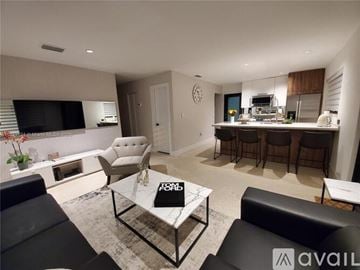 Miami house for rent - A modern living room with a black leather couch and a glass coffee table.