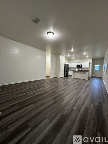 San Antonio house for rent - A spacious room with wooden flooring and a kitchen area in the background.