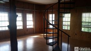 Spicewood house for rent - A spiral staircase in a room with wooden walls and windows.