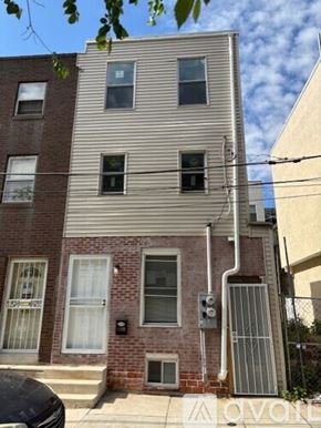 Philadelphia house for rent - A building with a grey facade and a brick base has a white awning.