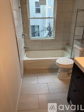 Philadelphia house for rent - A bathroom with a toilet, tub, and window.