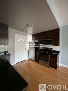Chicago apartment for rent - A kitchen with a black counter top and wooden floors.