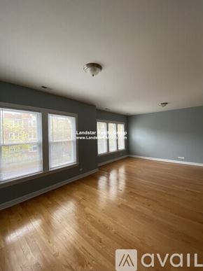 Chicago apartment for rent - A spacious room with wooden flooring and large windows.