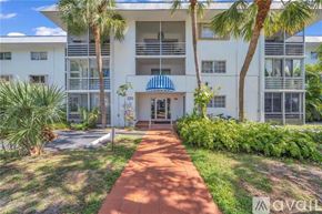 Key Biscayne apartment for rent - A white building with a blue awning and a brick pathway leading to the entrance.