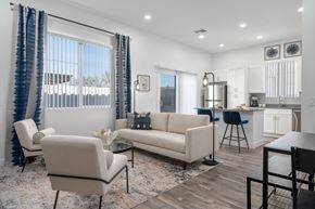 Phoenix apartment for rent - A modern living room with comfortable seating and a glass coffee table with a view into the spacious kitchen with stainless steel appliances and a kitchen island at Allero 59 Apartments, Phoenix 85035