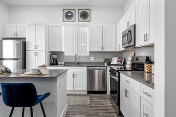 Phoenix apartment for rent - A kitchen with a blue chair and white cabinets.