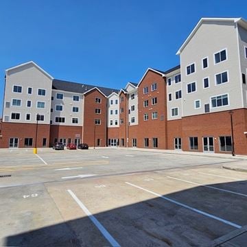 Elmwood Park apartment for rent - A parking lot in front of a multi-story brick building.