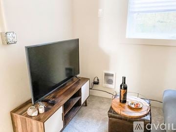 Portland house for rent - A living room with a television and a glass table with food and a bottle of wine on it.