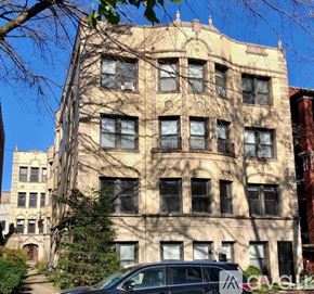 Chicago apartment for rent - A beige building with a tree in front of it.