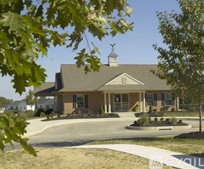 Mountville townhouse for rent - A house with a brown roof and a white chimney is surrounded by trees and bushes.