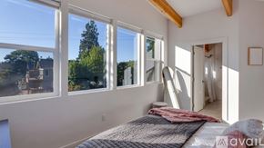 Portland apartment for rent - A bedroom with a large bed and a view of the backyard through the windows.